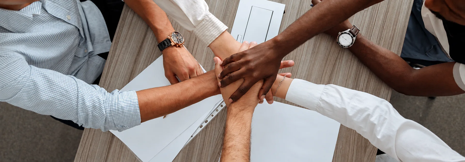 Team members joining hands over a meeting table